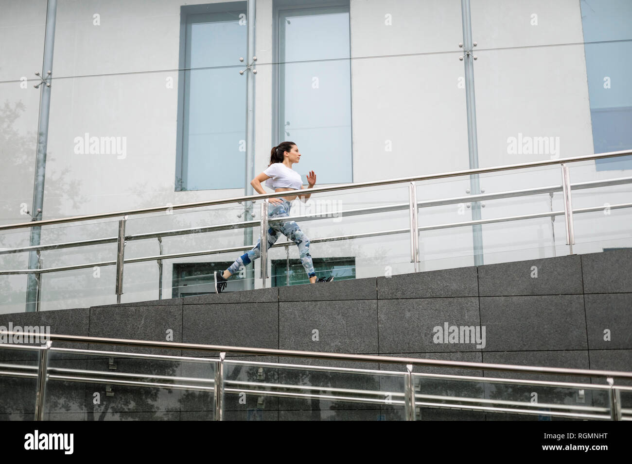 Giovane donna che corre lungo edificio della città Foto Stock