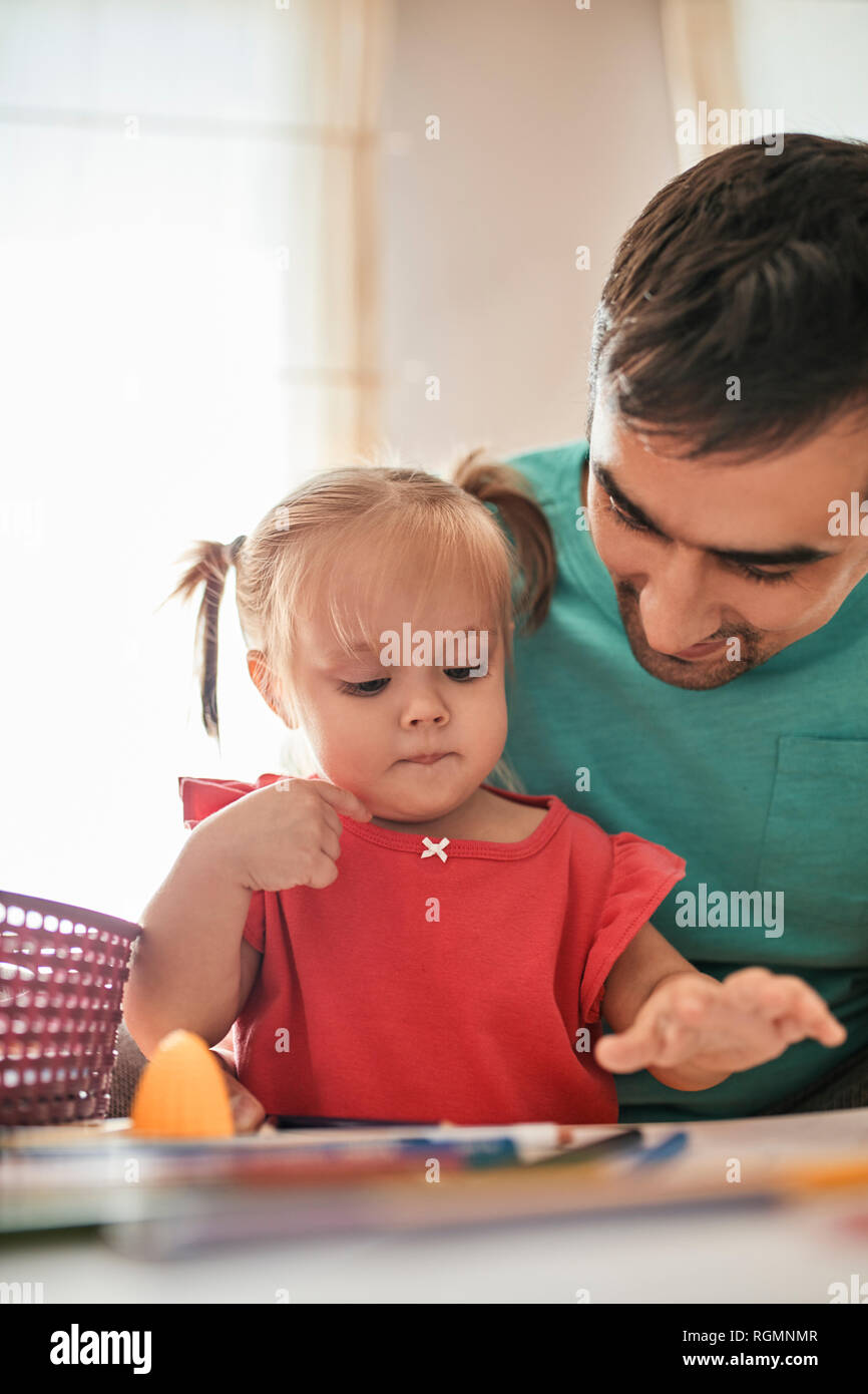 Ritratto di bambina Disegno con matite colorate mentre suo padre osservando il suo Foto Stock