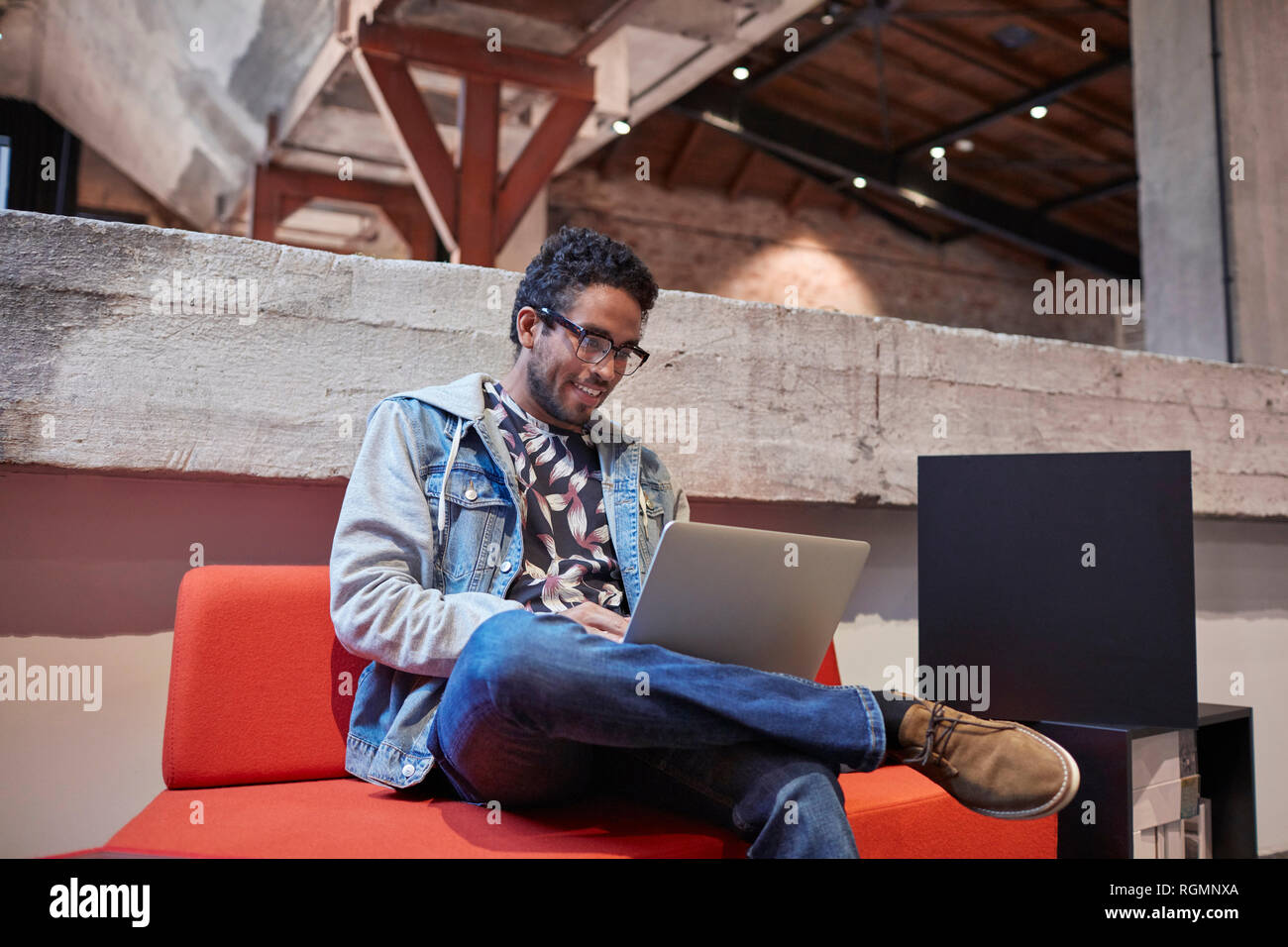 Giovane uomo che lavora in creativi azienda start-up, utilizzando laptop Foto Stock