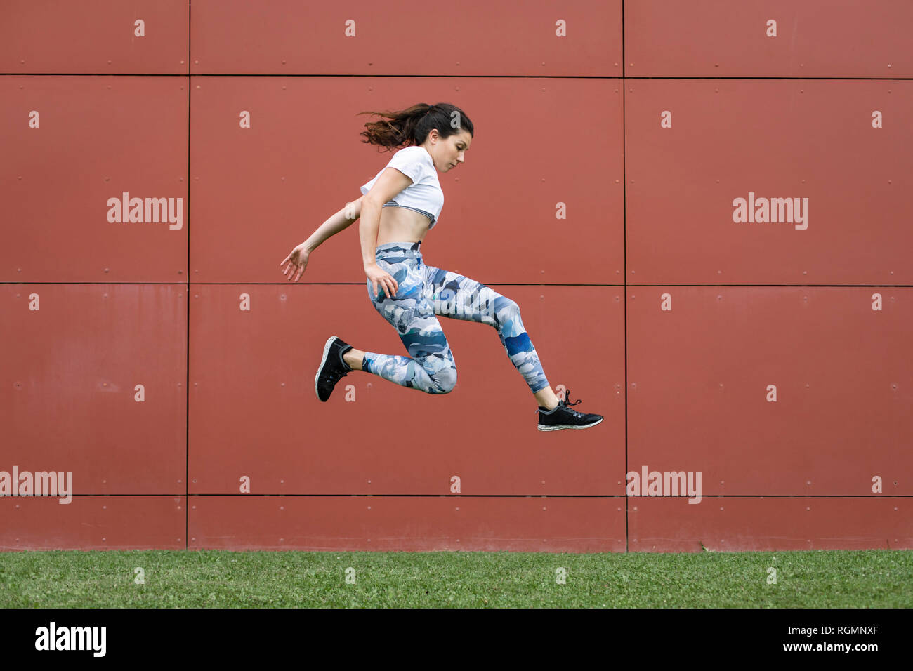Montare la giovane donna jumping midair Foto Stock