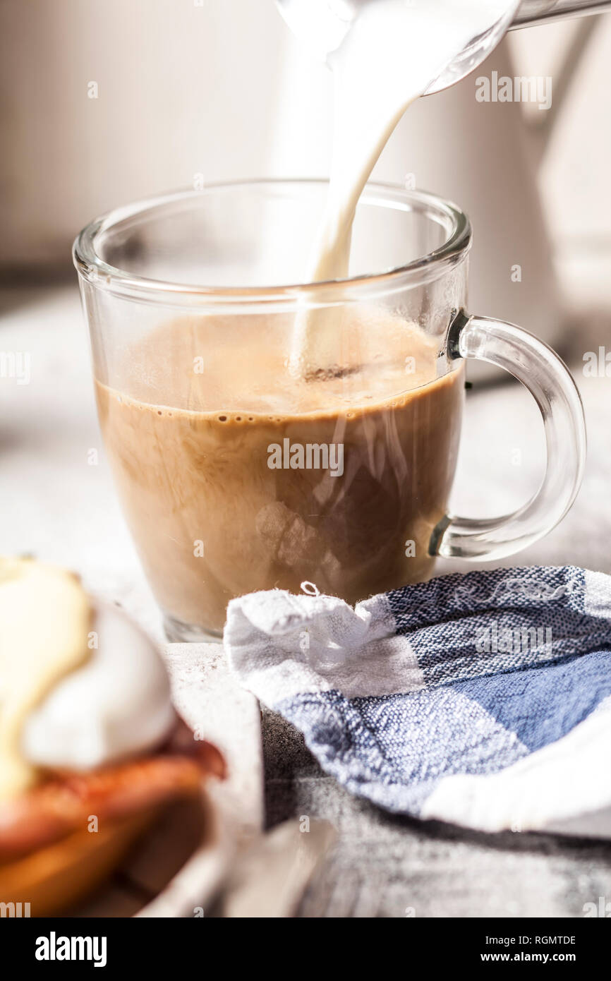 Versare il latte in una tazza di caffè Foto Stock