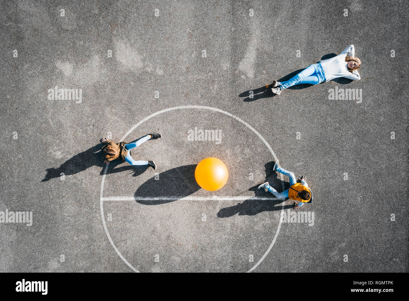 Austria, antenna, vista del campo da basket con grande palla, madre giacente sul terreno, bambini seduti Foto Stock