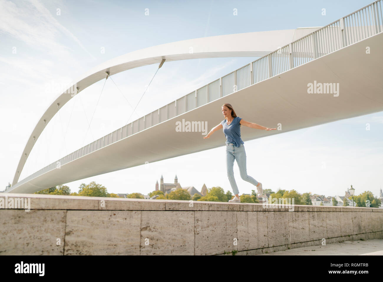 Paesi Bassi, Maastricht, giovane donna in equilibrio su una parete in corrispondenza di un ponte Foto Stock