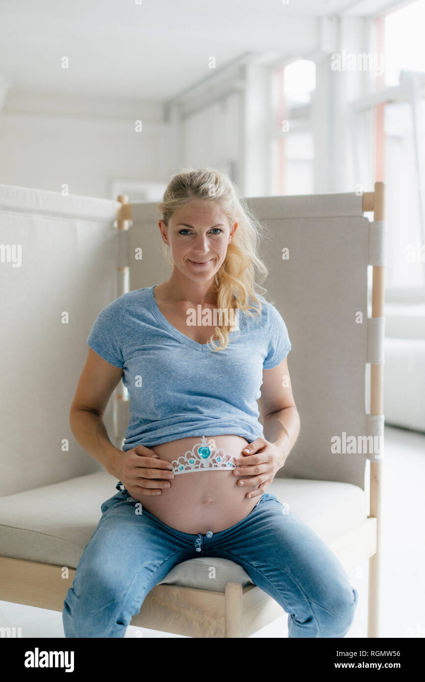 Ritratto di sorridere donna incinta holding tiara al suo ventre Foto Stock