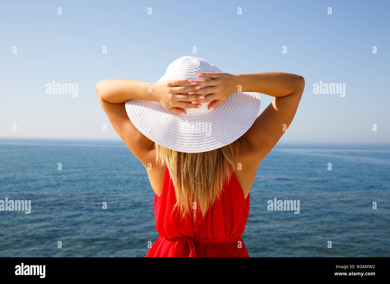 Donna bionda in abito rosso con il cappello bianco presso la spiaggia di Cipro. Foto Stock