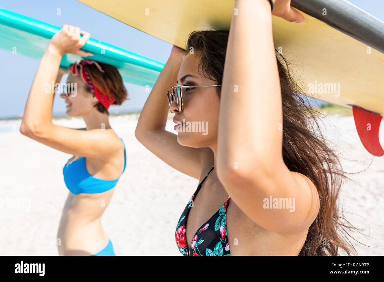 Gli amici di andare a fare surf, portando le tavole da surf sulla parte superiore delle teste Foto Stock