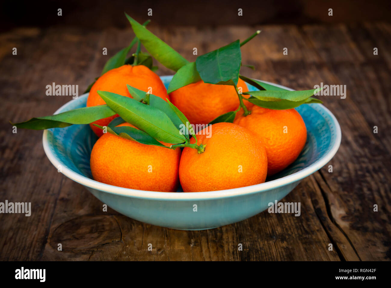 Le clementine in ciotola su legno Foto Stock