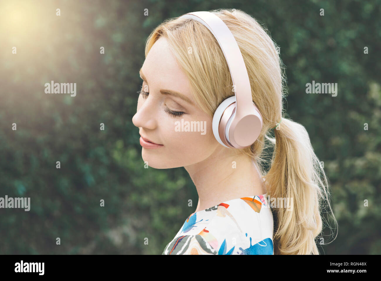 Bianco giovane donna ha gli occhi chiusi e viene spostato mediante l'ascolto di musica sul suo cuffie Foto Stock