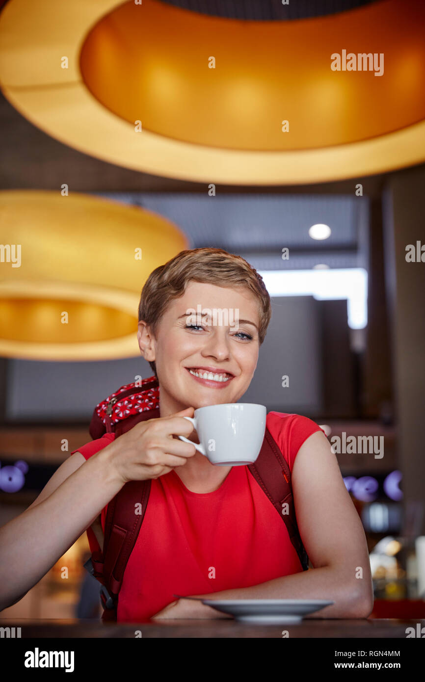 Ritratto di donna sorridente con zaino in un cafe Foto Stock