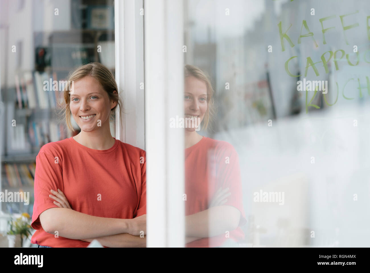 Ritratto di sorridente giovane donna alla porta francese in un cafe Foto Stock