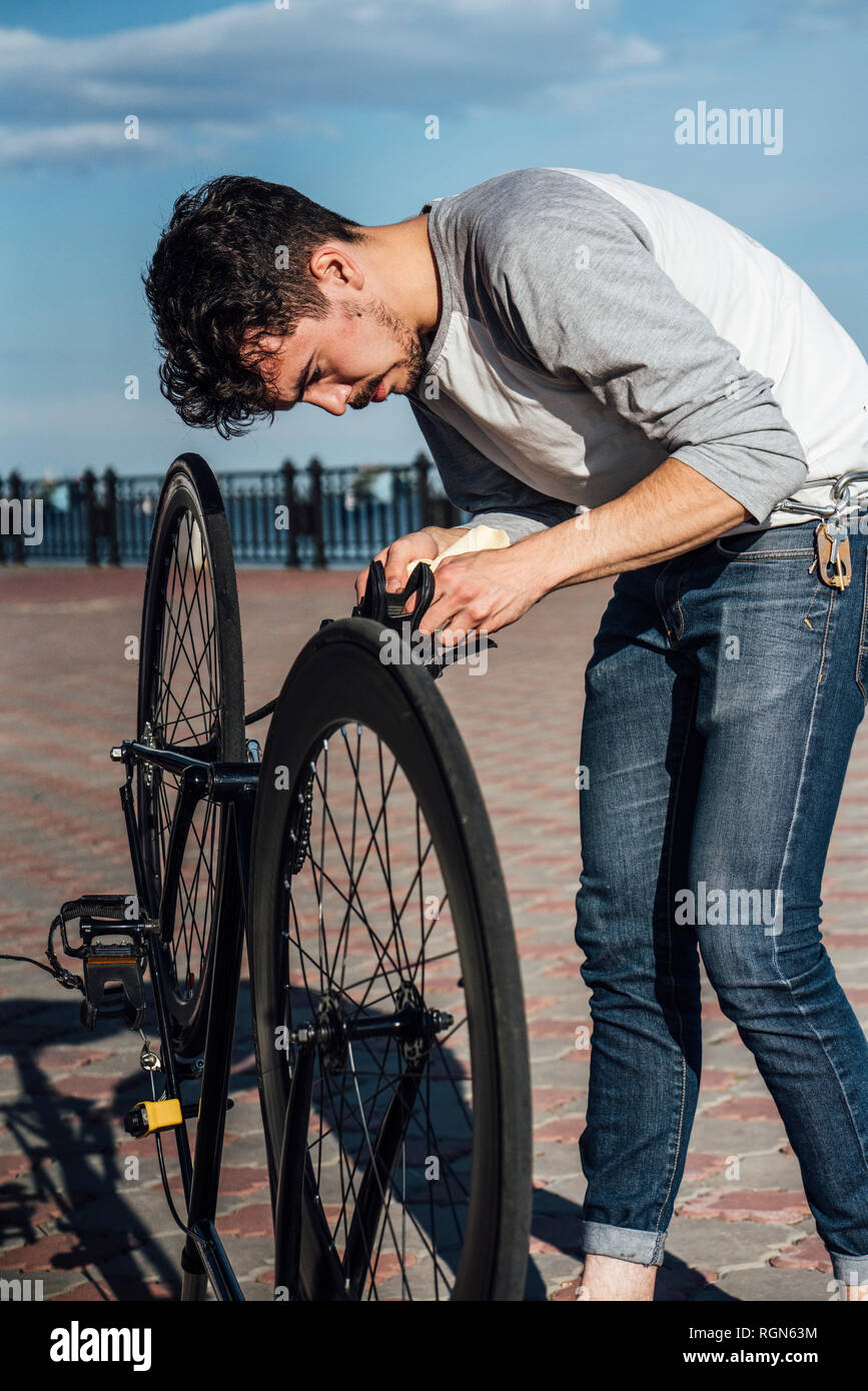 Giovane uomo che ripara commuter fixie bike Foto Stock