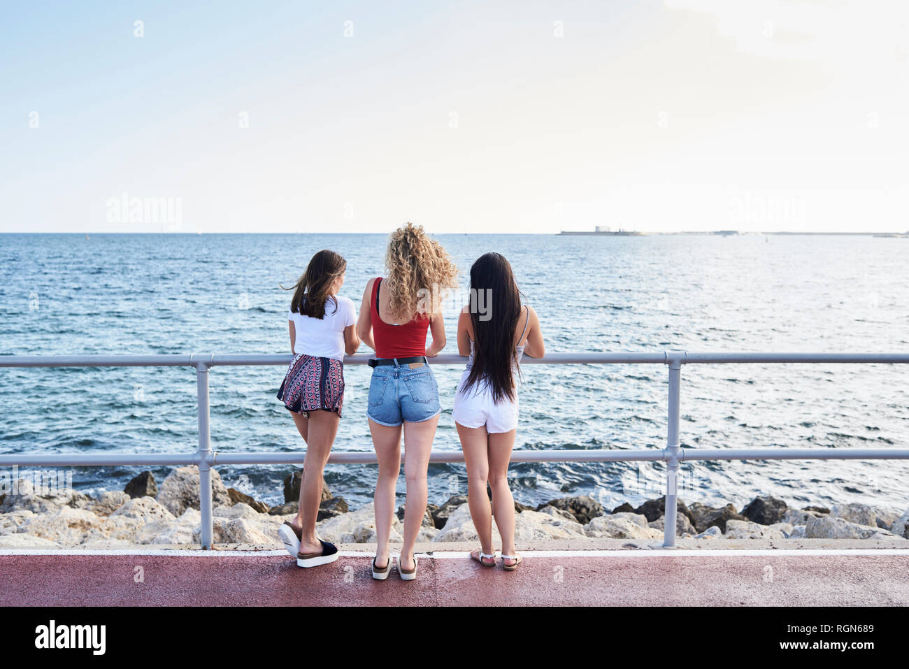 Spagna, Mallorca, Palma, vista posteriore di tre giovani donne in piedi al mare Foto Stock
