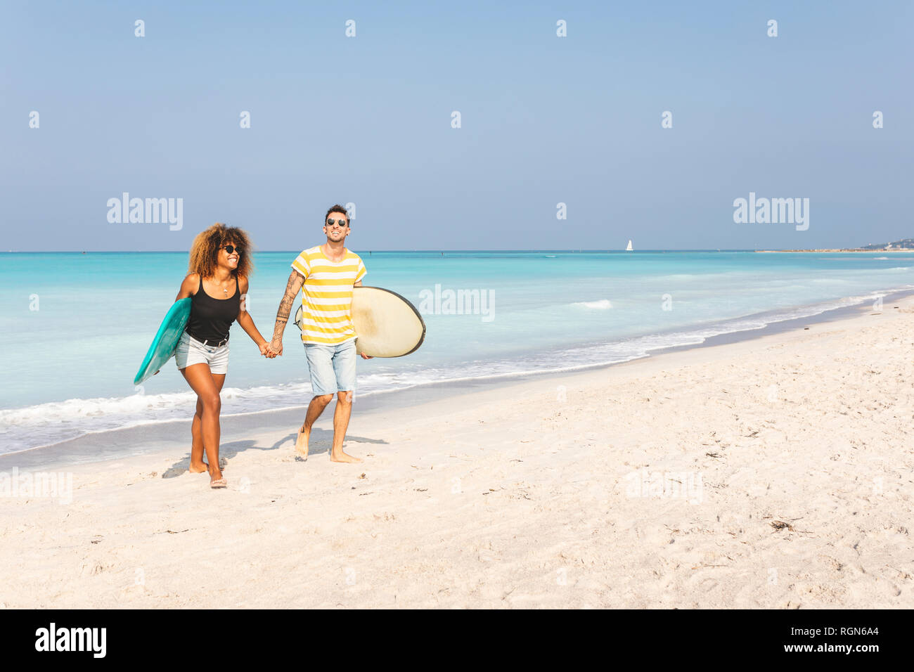 Paio di camminare sulla spiaggia, portando le tavole da surf Foto Stock