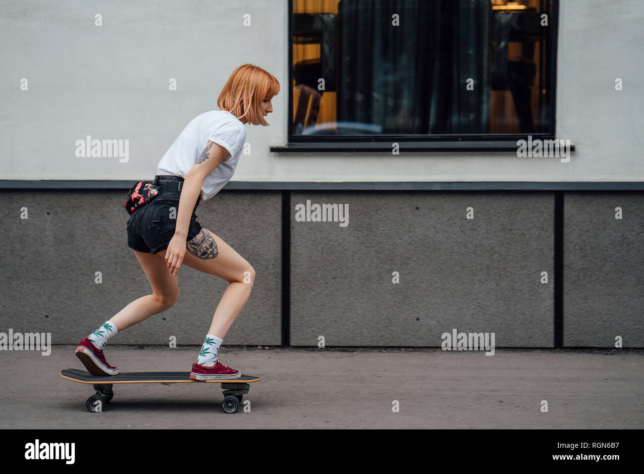 Giovane donna cavallo carver skateboard sul marciapiede Foto Stock