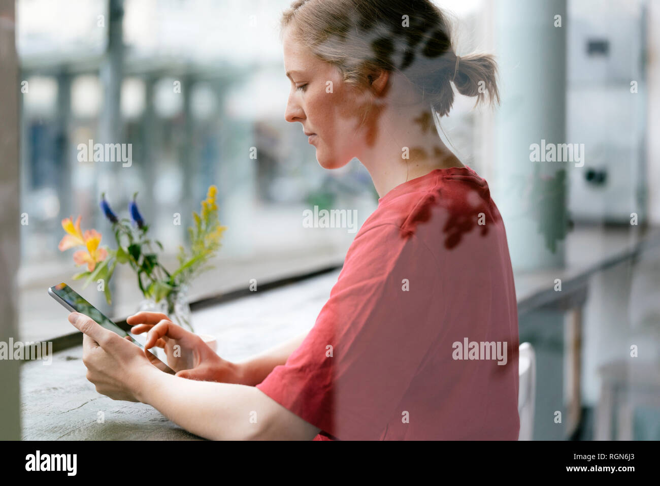 Giovane donna con tavoletta nella finestra in un cafe Foto Stock