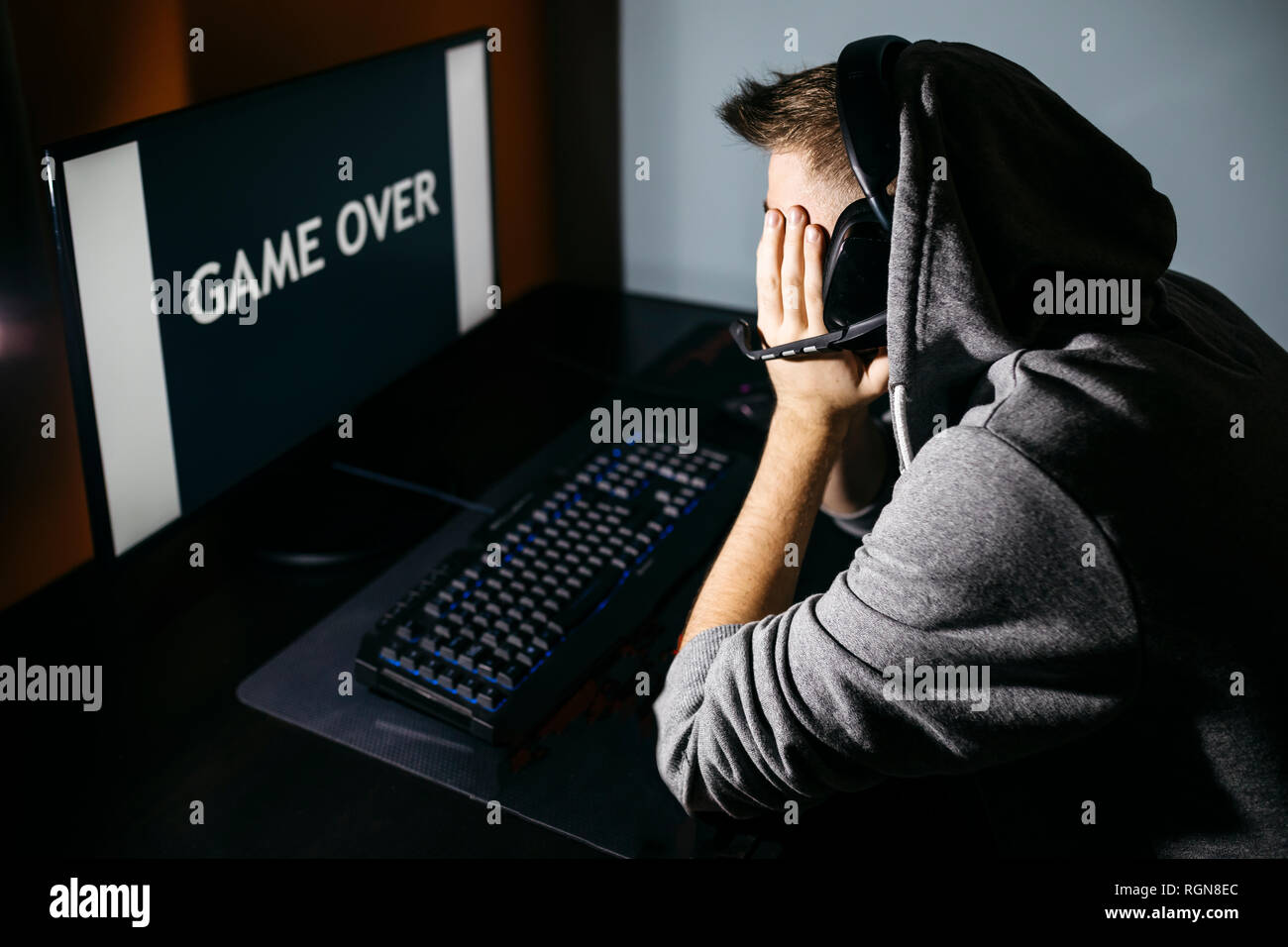 Giovane uomo seduto al PC, guardando lo schermo con gioco sul testo Foto Stock