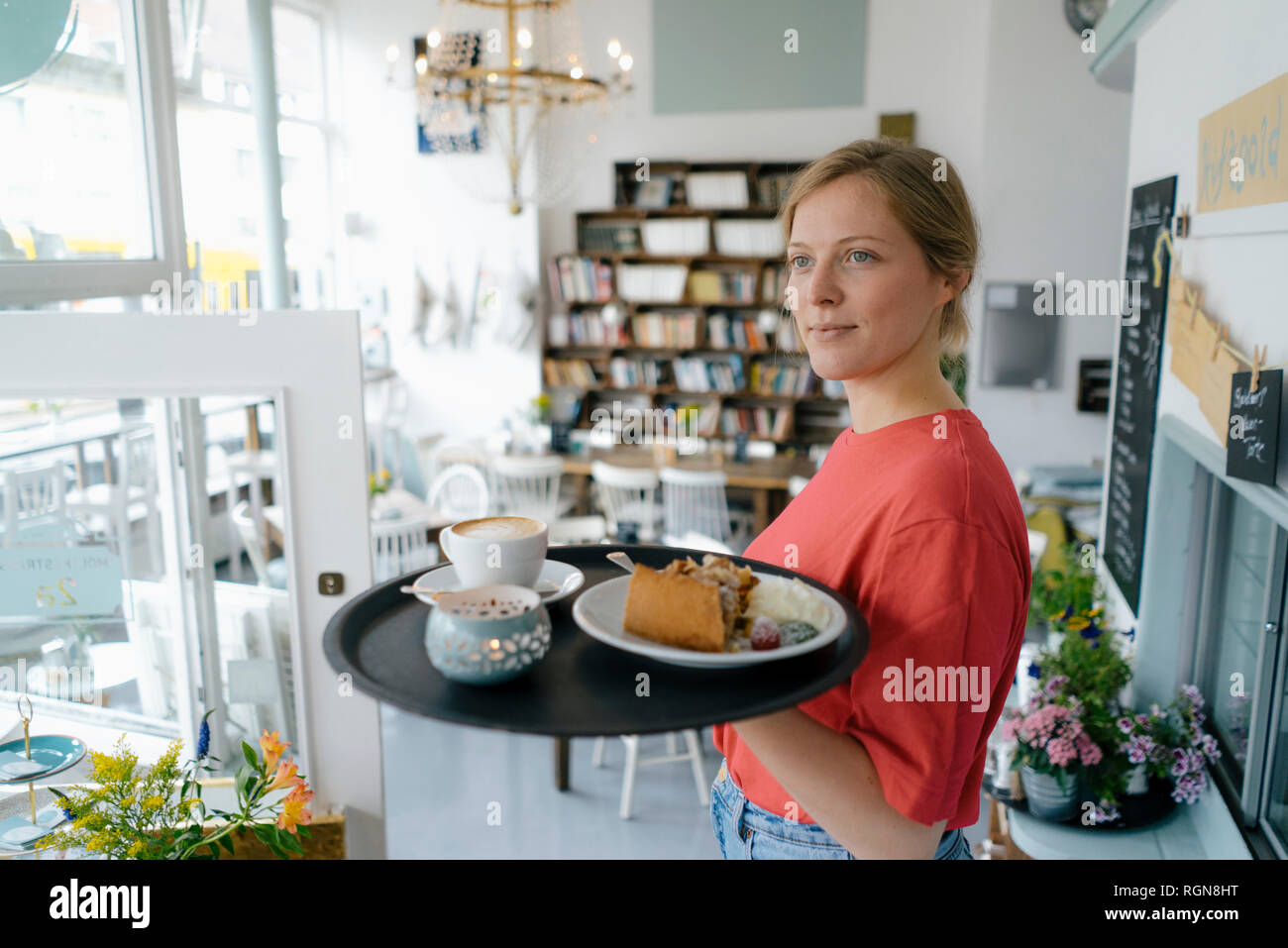 Giovane donna che serve caffè e una fetta di torta in una caffetteria Foto Stock