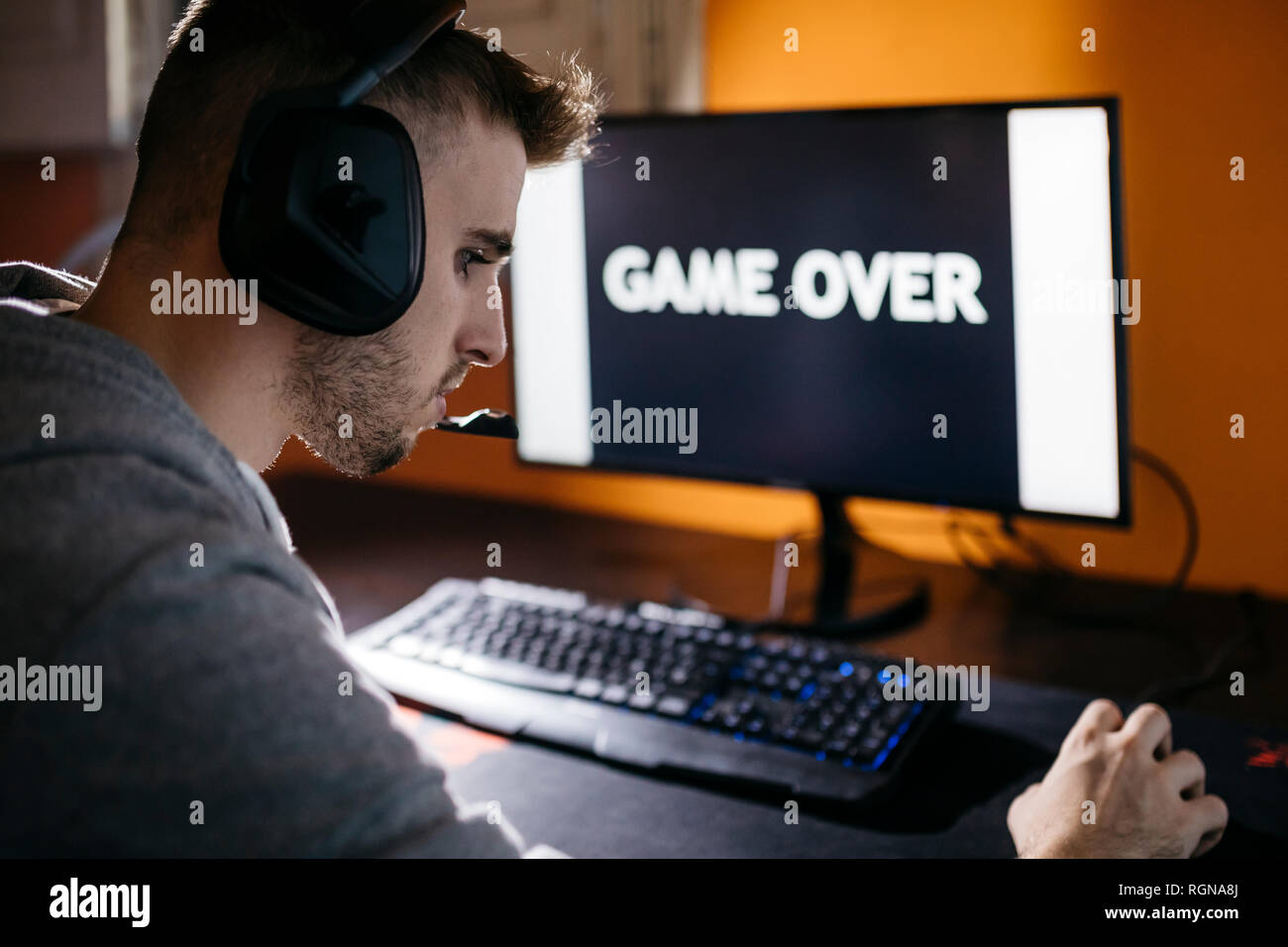 Giovane uomo seduto al PC, guardando lo schermo con gioco sul testo Foto Stock