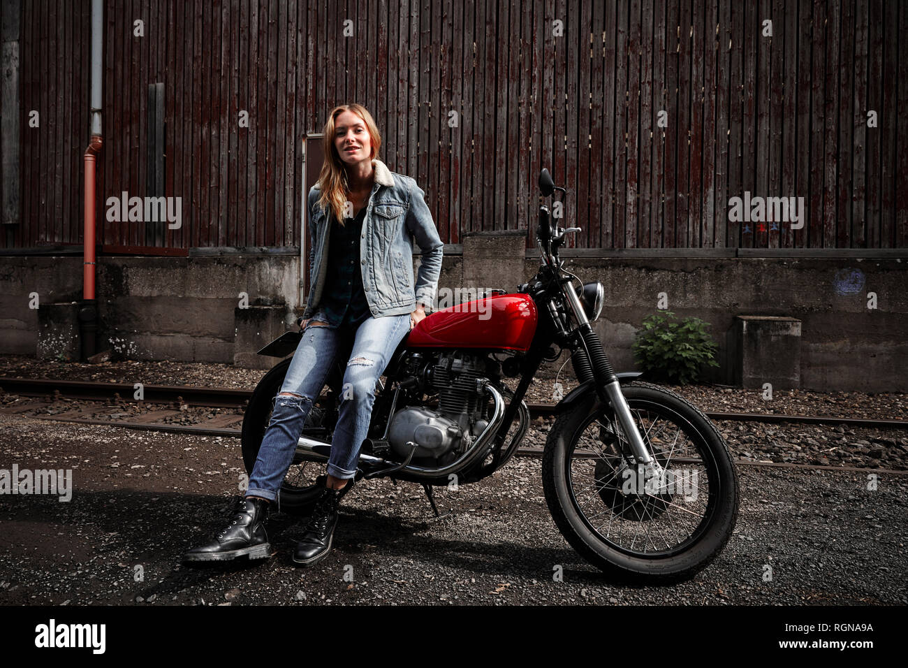 Ritratto di fiducioso giovane donna con moto Foto Stock
