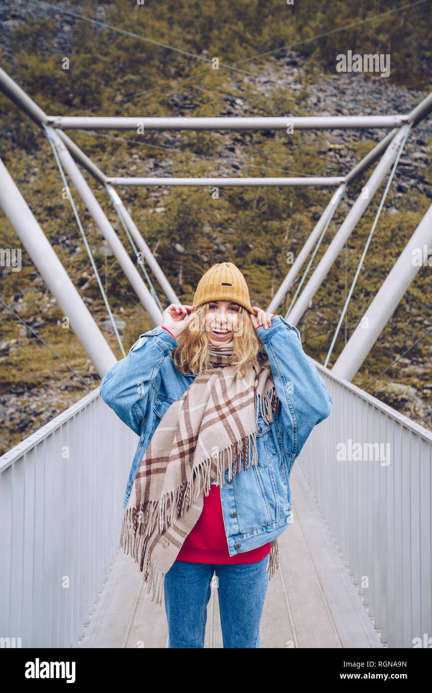 Giovane donna in piedi su un ponte ventilato, tenendo il suo cap Foto Stock
