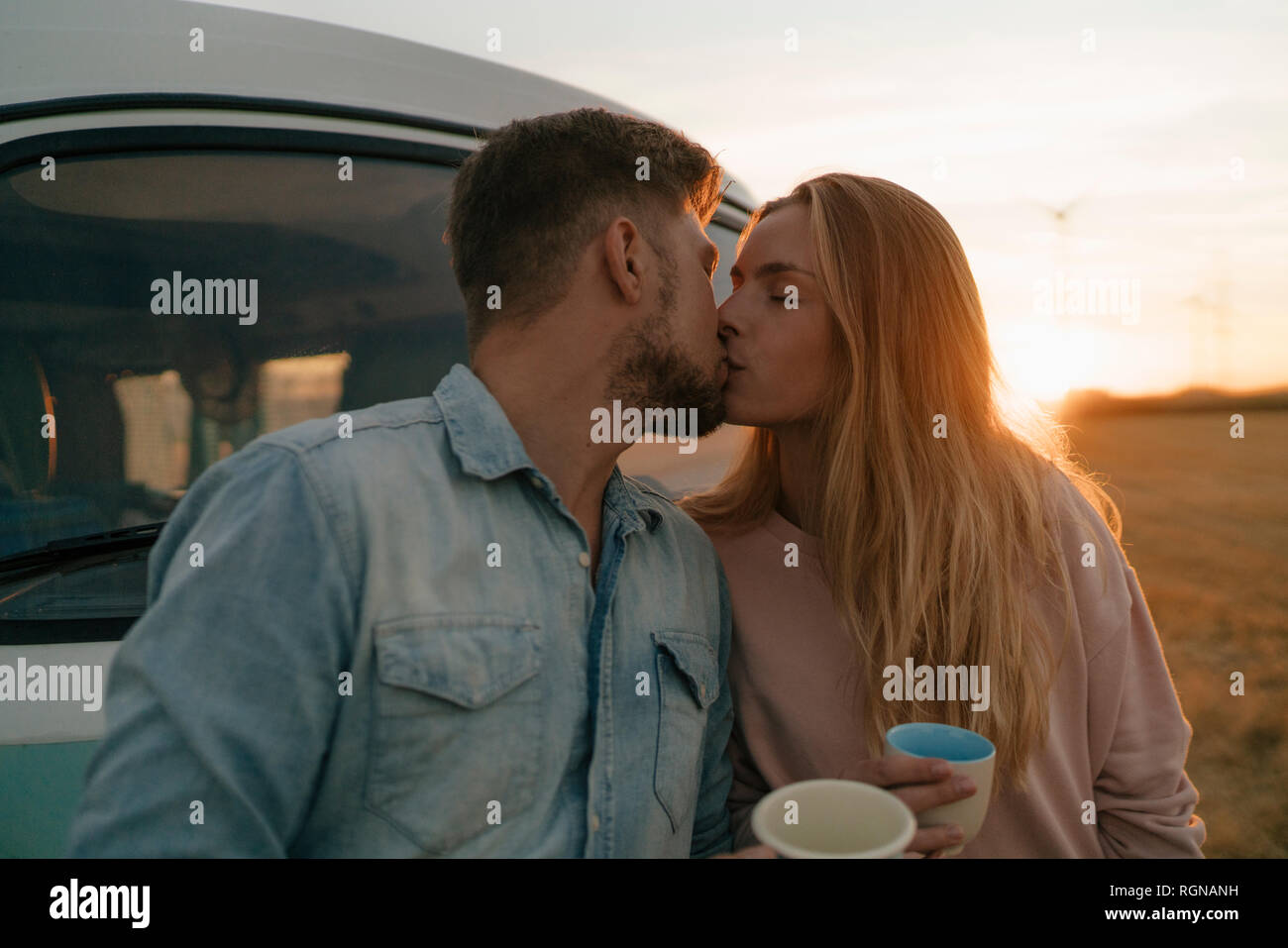 Coppia giovane kissing a camper van nel paesaggio rurale Foto Stock
