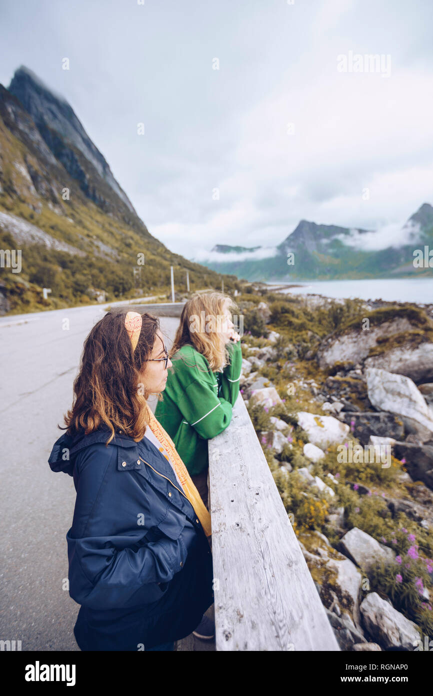 Norvegia, Senja, due giovani donna in piedi sul bordo della strada guardando a vista Foto Stock