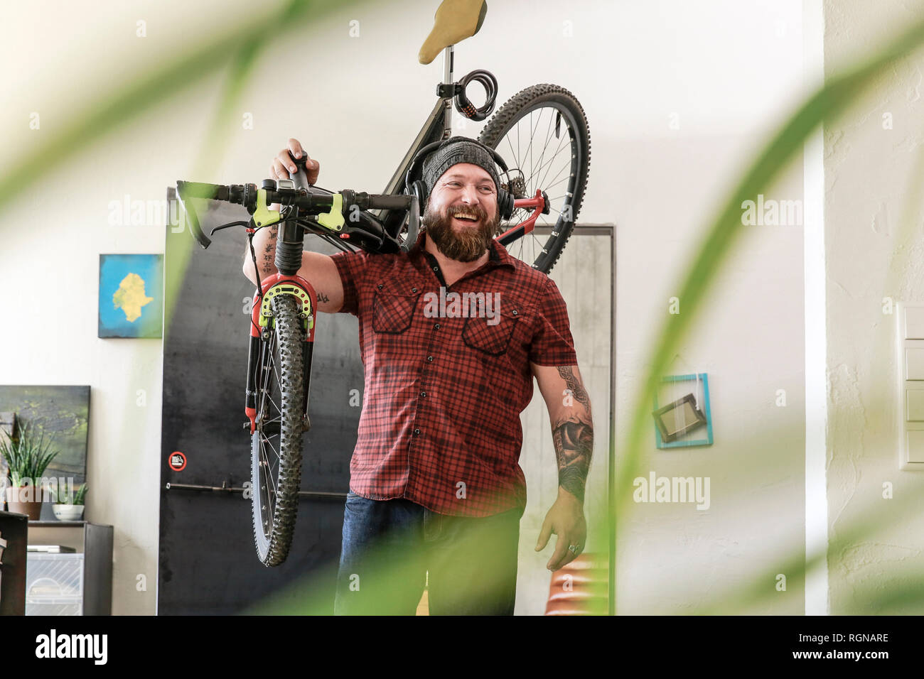 Laughing Man che indossano le cuffie che trasportano in bicicletta in ufficio Foto Stock