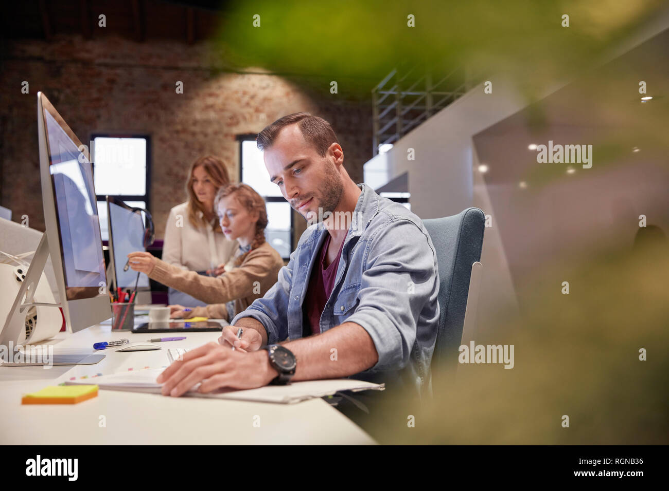 Uomo che lavora alla scrivania in ufficio, sorridente Foto Stock