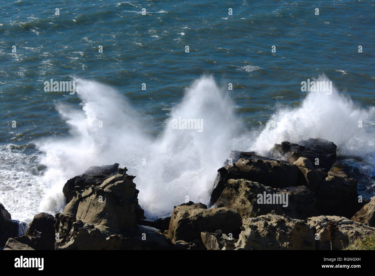 Le onde che si infrangono sulle rocce della costa Foto Stock