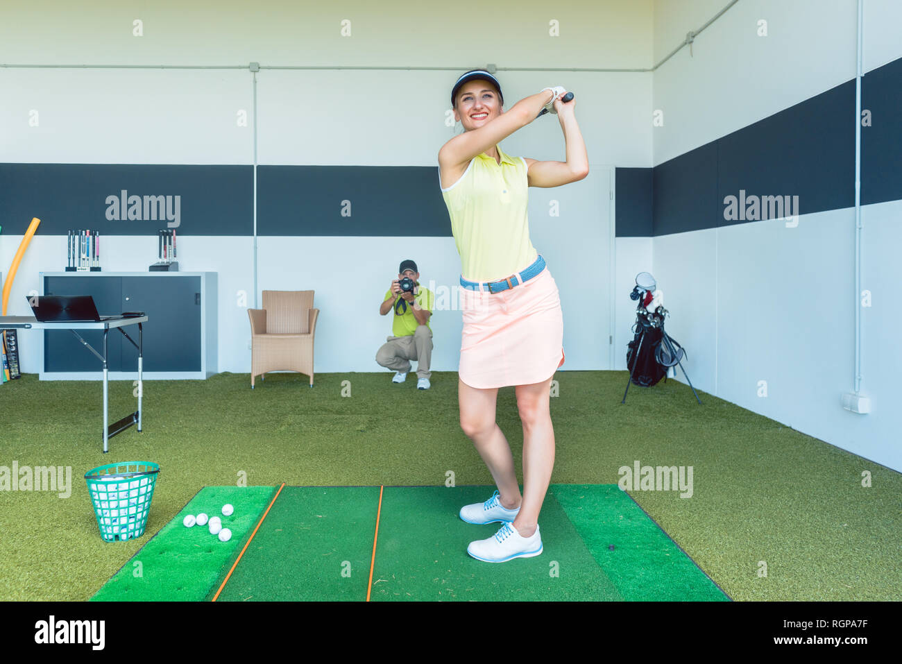 Montare donna praticare golf swing durante la classe professionale per interni Foto Stock