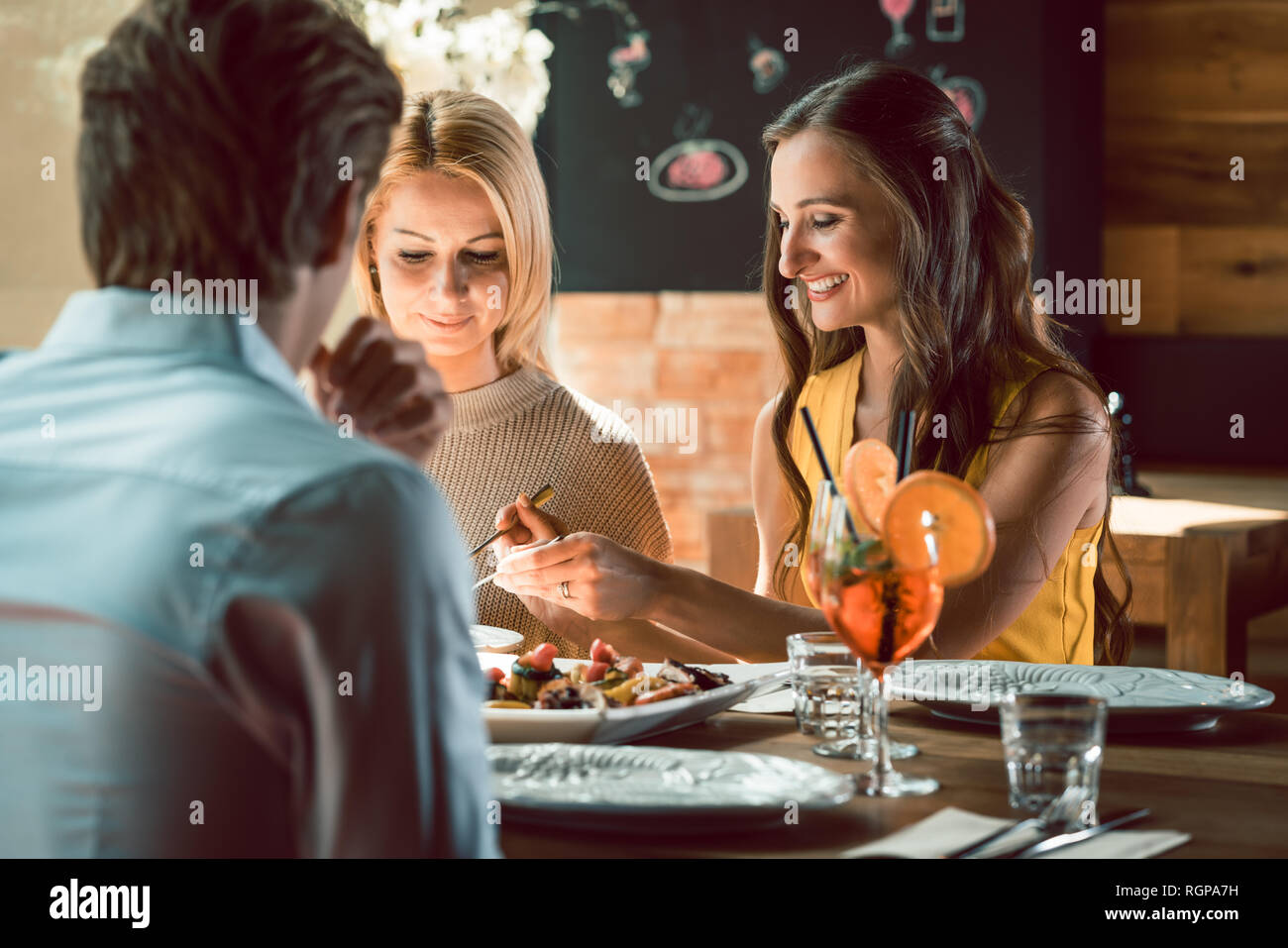 Giovane donna sorridente durante il pranzo con i suoi migliori amici presso il ristorante Foto Stock