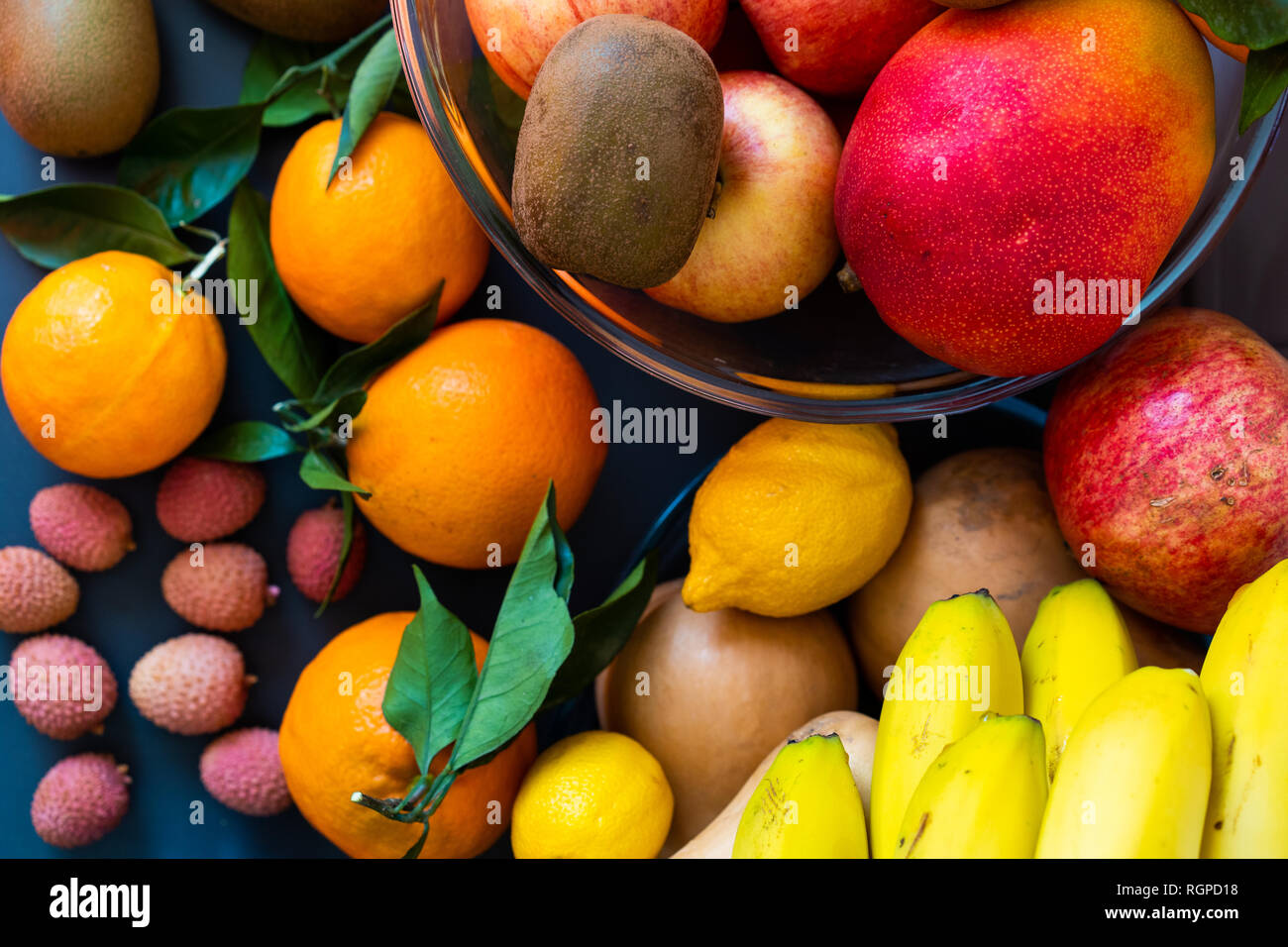 Raccolta di diversi gustosi freschi maturi frutti tropicali in ciotole e piatti sul tavolo vicino a parete Foto Stock