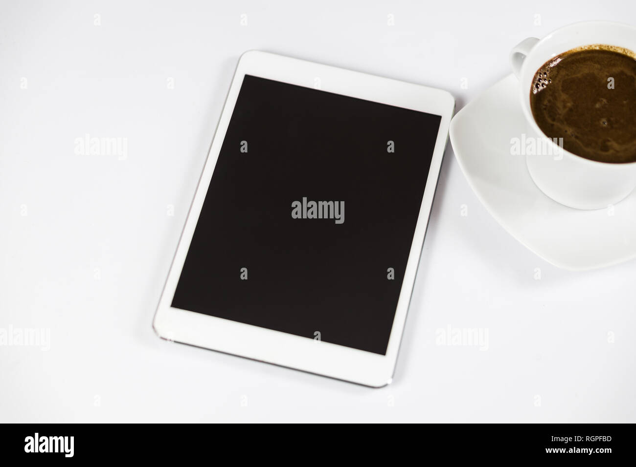 Computer tablet con schermo vuoto accanto al caffè. Il tablet è sul tavolo bianco. Vista dall'alto. Close-up. Foto Stock