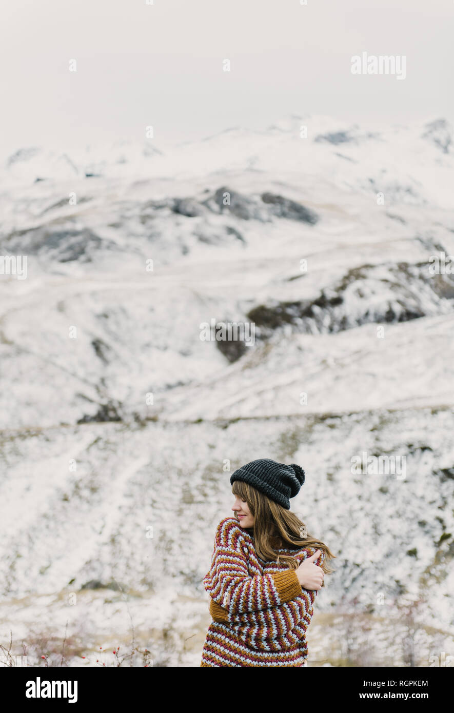 Attraente ragazza in maglione e hat con due mani incrociate vicino colle su sfondo sfocato nei Pirenei Foto Stock