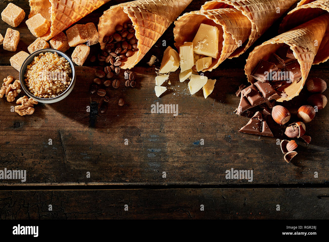 Coni riempita di cioccolato, caramello, caffè contro lo sfondo di legno Foto Stock