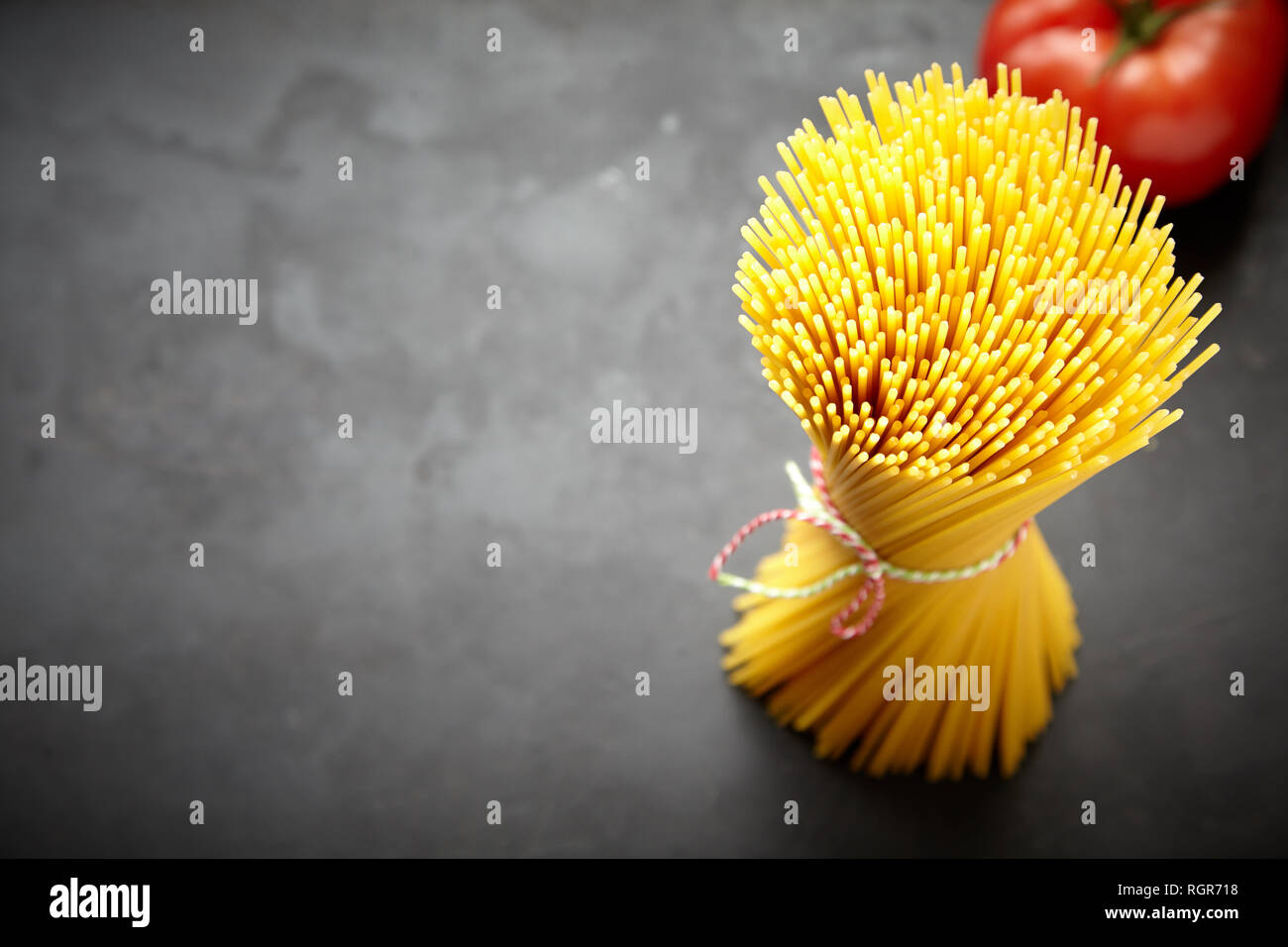 Mazzetto di materie spaghetti in vista ravvicinata con il pomodoro in background Foto Stock