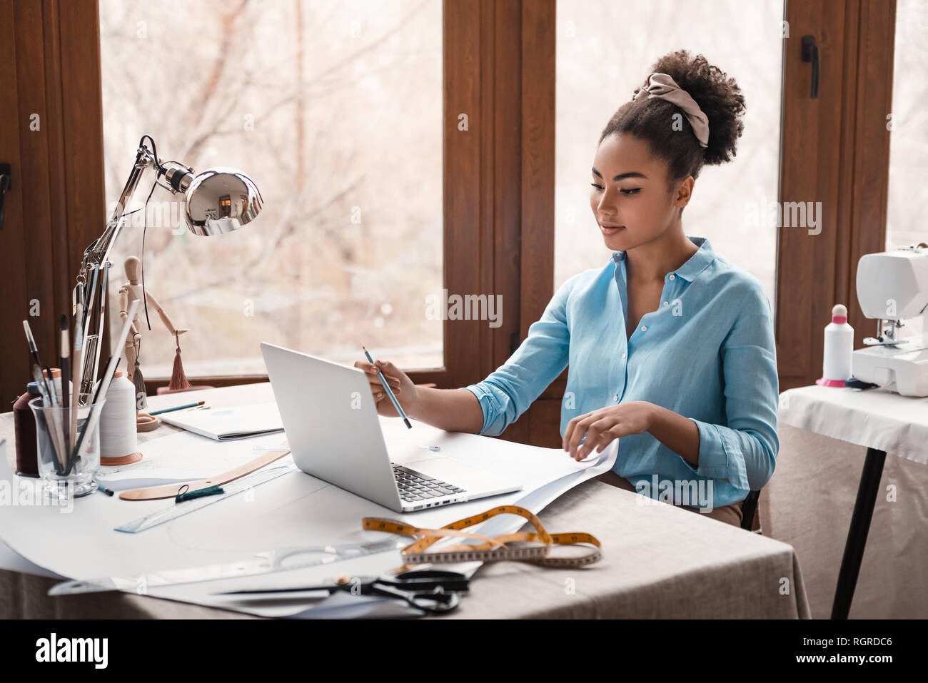 Cominciamo a creare. La stilista lavora con il computer portatile in studio di design. Giovane donna africana stylist all'interno di edificio per uffici Foto Stock