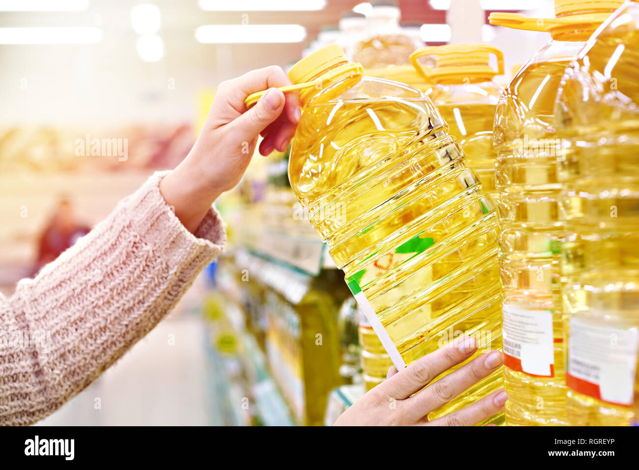 Acquirente prende l'olio di semi di girasole dal ripiano in negozio Foto Stock