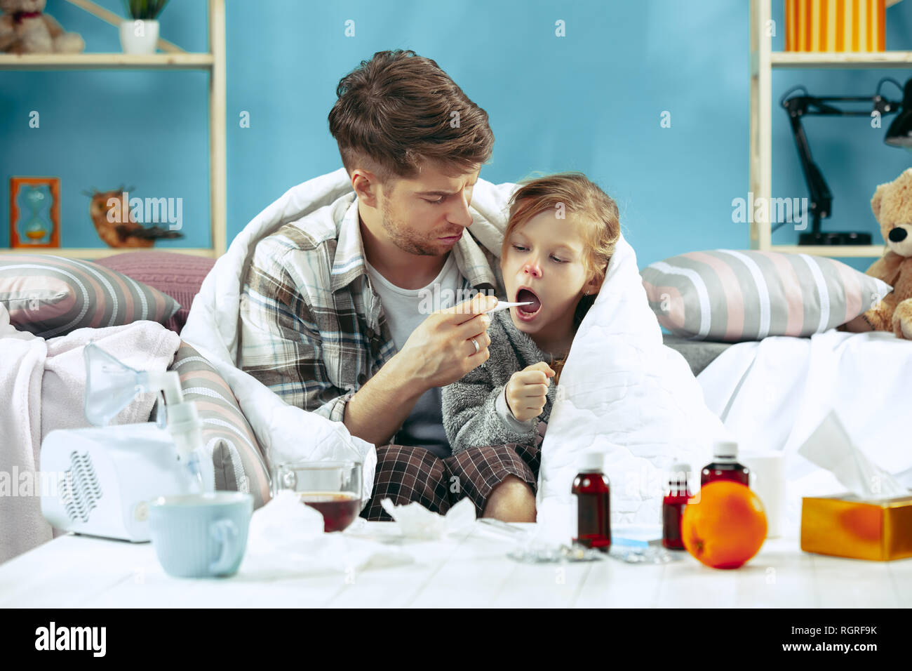 Uomo malato con la figlia a casa. Il trattamento a casa. Lottare con una malattia. Delle cure mediche. Famiglia iIlness. L'inverno, influenza, salute, il dolore, la paternità, il concetto di relazione. Relax a casa Foto Stock