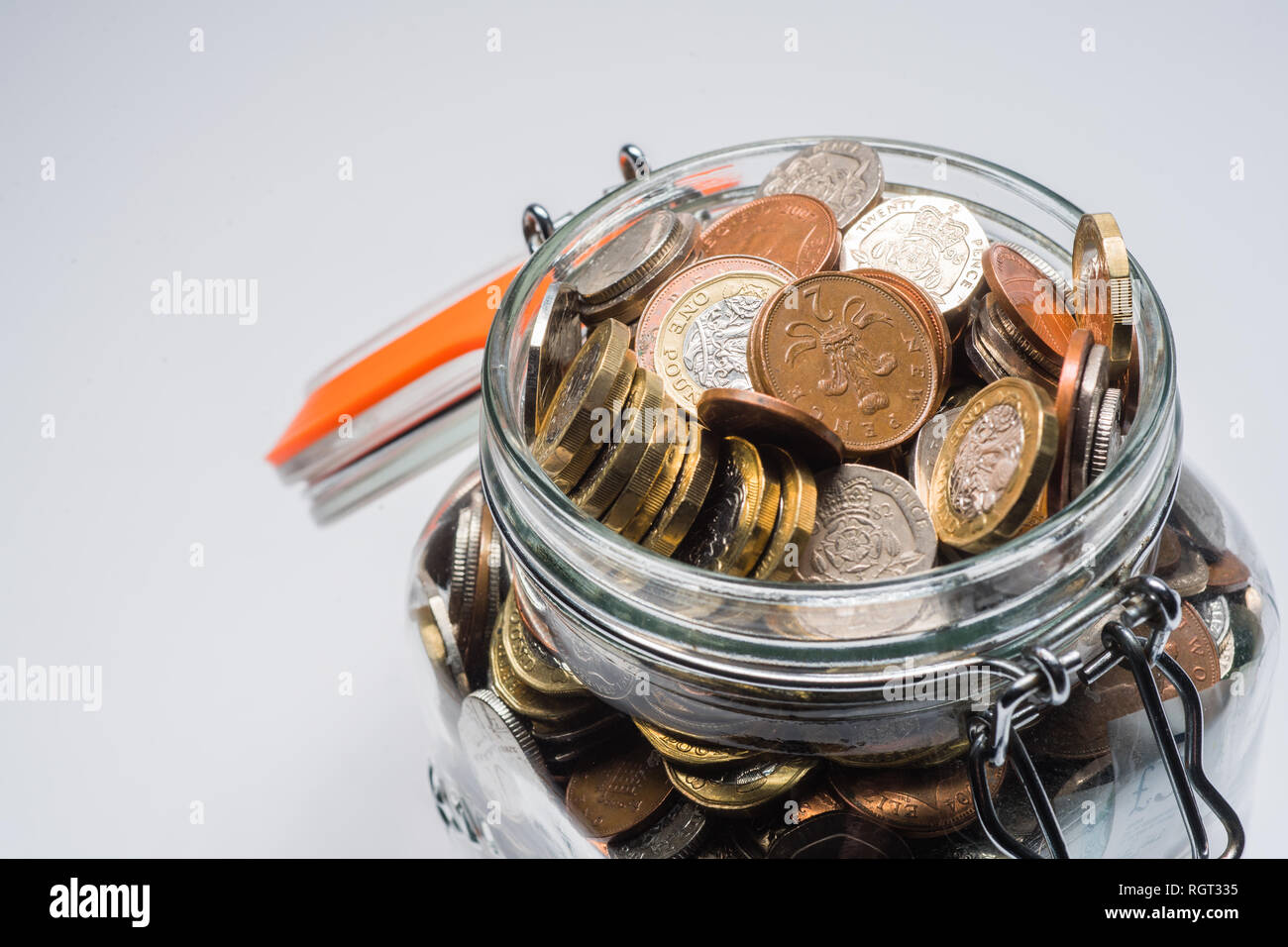 Risparmi REGNO UNITO - un vetro vaso di storage completamente pieno di british delle monete e delle banconote, salvati fino. Concetto illustrazione per la pianificazione previdenziale, giornata piovosa fondo di fondi di emergenza, home banking, in contanti, ricchezza accumulata Foto Stock
