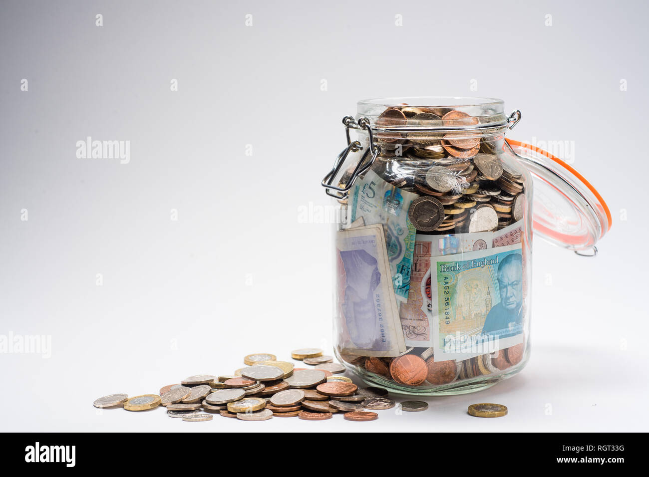 Risparmi REGNO UNITO - un vetro vaso di storage completamente pieno di british delle monete e delle banconote, salvati fino. Concetto illustrazione per la pianificazione previdenziale, giornata piovosa fondo di fondi di emergenza, home banking, in contanti, ricchezza accumulata Foto Stock