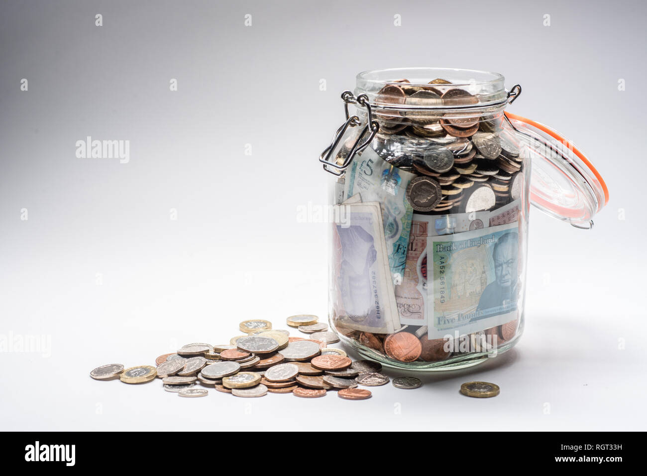 Risparmi REGNO UNITO - un vetro vaso di storage completamente pieno di british delle monete e delle banconote, salvati fino. Concetto illustrazione per la pianificazione previdenziale, giornata piovosa fondo di fondi di emergenza, home banking, in contanti, ricchezza accumulata Foto Stock