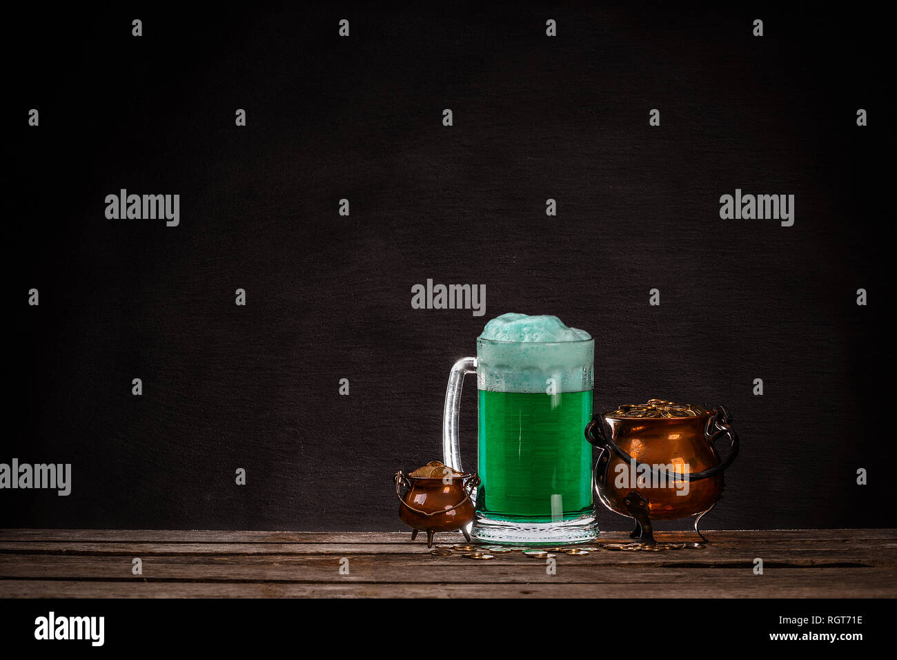 Vaso con monete e birra verde sul tavolo di legno; il giorno di San Patrizio concept Foto Stock