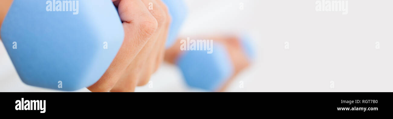 Close up panorama di banner per il web di giovane donna o ragazza mani femminili esercizio di sollevamento pesi blu in una palestra Foto Stock