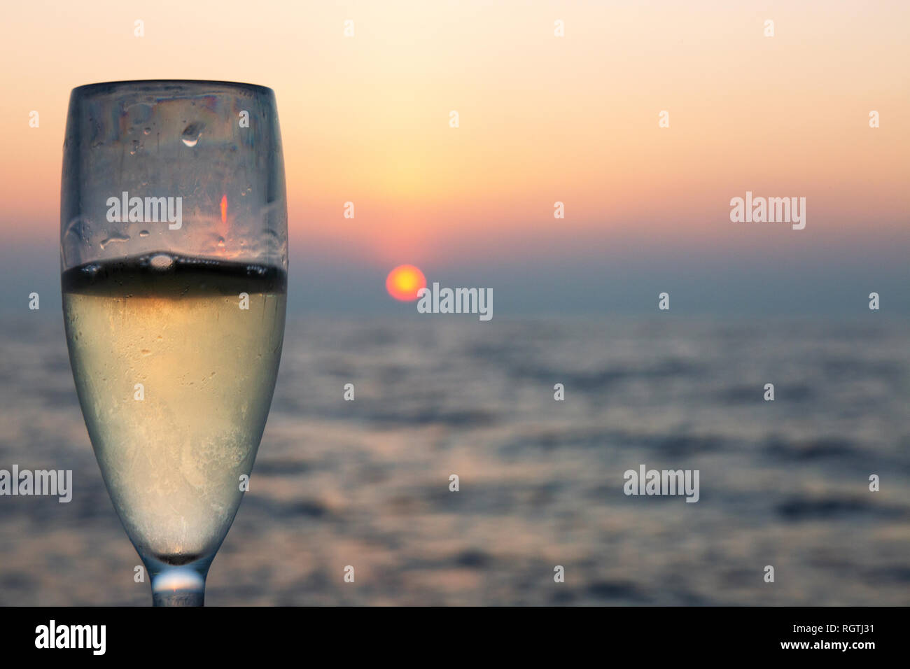 Un bicchiere di champagne con tramonto sull'oceano, Maldive, Oceano Indiano Asia Foto Stock
