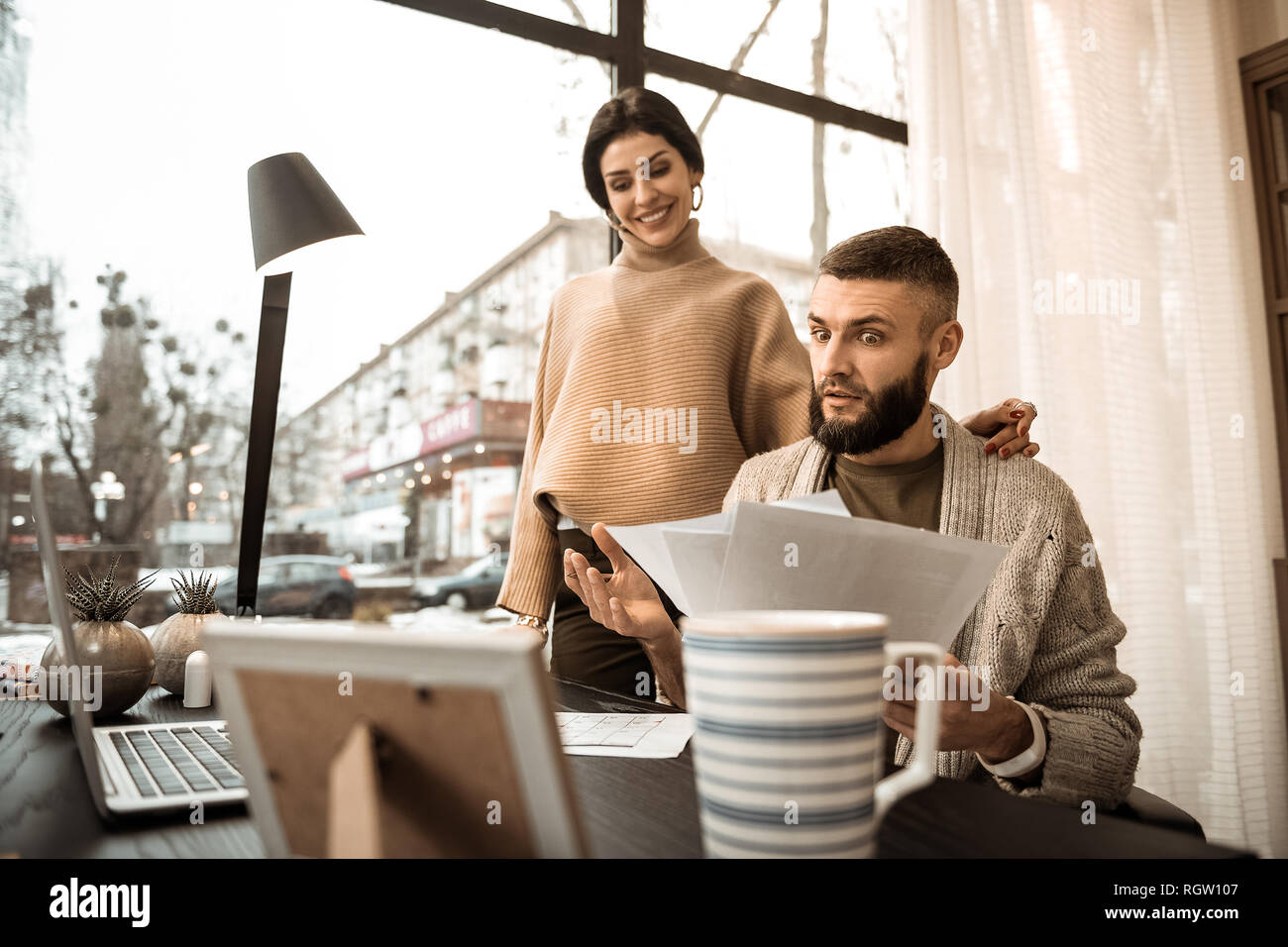 Scioccato barbuto ragazzo che trasportano le carte e mostrando loro a sua moglie Foto Stock