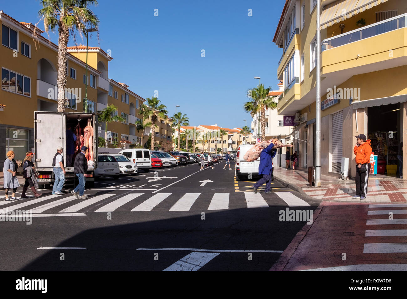 Per la consegna di carni, carcasse di suino viene scaricato da un furgone refrigerato e consegnato a un negozio di macellaio in Playa San Juan, Tenerife, Isole Canarie, Spai Foto Stock