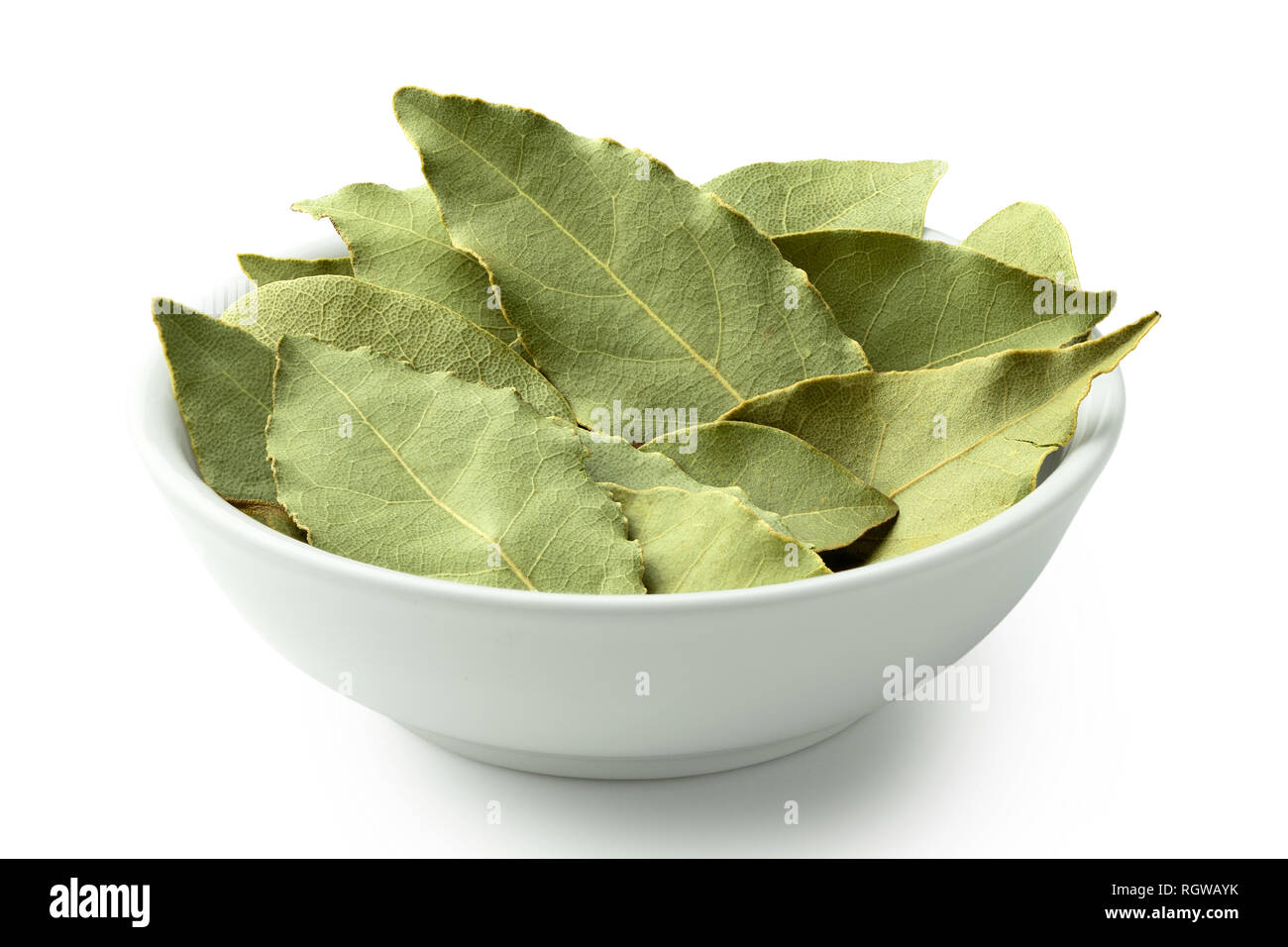 Essiccata foglie di alloro in ceramica bianca recipiente isolato su bianco. Foto Stock