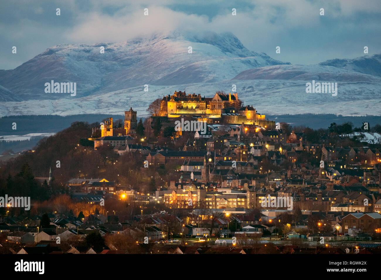 Il Castello di Stirling e la città di Stirling al crepuscolo con montagne coperte di neve (Stuc un Chroin ) a distanza Foto Stock