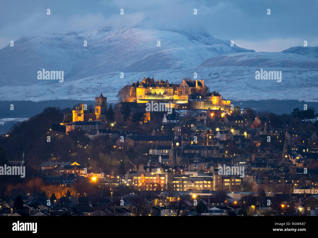 Il Castello di Stirling e la città di Stirling al crepuscolo con montagne coperte di neve (Stuc un Chroin ) a distanza Foto Stock